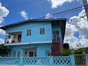 a blue house with a staircase in front of it at Pearls Place in Arima