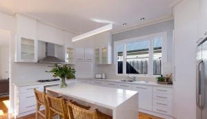 Una cocina blanca con una mesa y sillas blancas. en Wild Cherry on Wishart, en Port Fairy