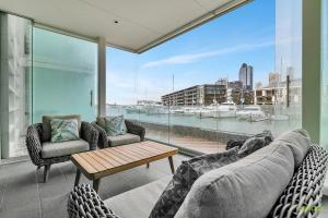a living room with couches and a table and a large window at QV Waterfront Apartment Viaduct Area - 503 in Auckland