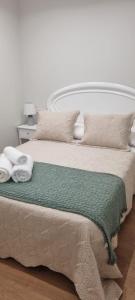 1 cama con manta verde y almohadas en CASA PEREIRAS, en Pontevedra