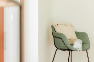 a green chair sitting next to a window at JARS Apartments - Casa do Bessa in Porto