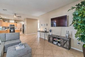 a living room with a couch and a tv on a wall at New Home Hot Tub, Grill, Games, 11 Mi to Strip! in Las Vegas