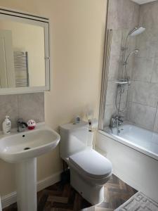 W łazience znajduje się toaleta, umywalka i prysznic. w obiekcie Cheerful 3 Bedroom Town House With Hot Tub w Blackpool
