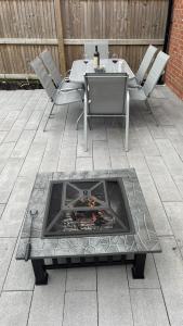 a fire pit on a patio with a table and chairs at Cheerful 3 Bedroom Town House With Hot Tub in Blackpool