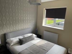 um quarto com uma cama branca e uma janela em Cheerful 3 Bedroom Town House With Hot Tub em Blackpool