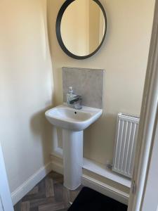 a bathroom with a sink and a mirror on the wall at Cheerful 3 Bedroom Town House With Hot Tub in Blackpool