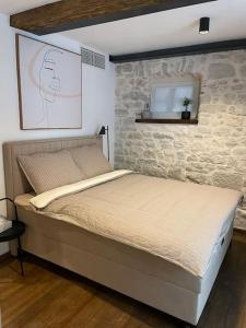 Ce lit se trouve dans une chambre dotée d'un mur en pierre. dans l'établissement Loft by Villa di Piazza - a home you won’t forget, à Višnjan