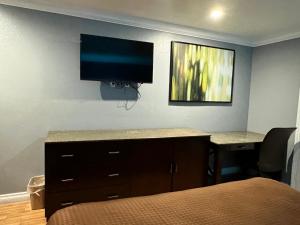 a bedroom with a desk with a television on the wall at BELL RESORT MOTEL in Bell