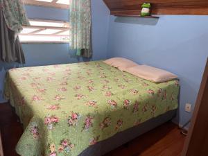 1 dormitorio con 1 cama con edredón verde y ventana en Chalé dos Ingleses, en Florianópolis