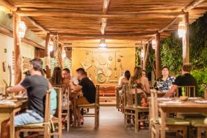 een groep mensen die aan tafel zitten in een restaurant bij La Cozinha Bungalow in Barra Grande