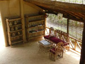 ein Zimmer mit Stühlen und einer Bank in einem Zimmer in der Unterkunft Bardia Eco Lodge in Bardiyā