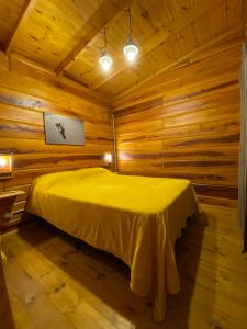 1 dormitorio con 1 cama en una cabaña de madera en Cabañas San Urbano 1 en Villa Yacanto