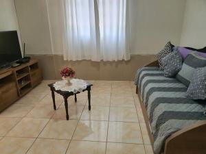 ein Wohnzimmer mit einem Sofa und einem Tisch mit Blumen darauf in der Unterkunft Casa Damasco in Florianópolis