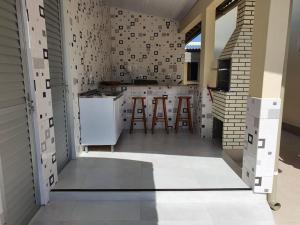 una cocina con armarios blancos y taburetes de bar en Casa Damasco, en Florianópolis