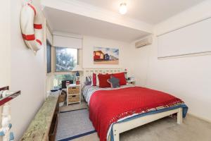 1 dormitorio con cama roja y ventana en Capes Coastal Charmer, en Cape Paterson