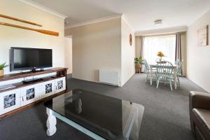 a living room with a television and a table at Braemar 9 in Forster