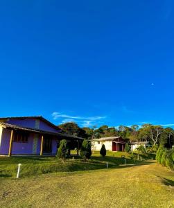 a house with a grassy yard next to a road at Pousada Vista Pedra Azul in Pedra Azul