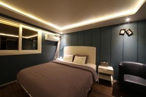 a bedroom with a large bed and a chair at Hotel Frenchcode in Busan