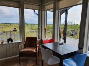 um quarto com uma mesa, cadeiras e janelas em Adorable cosy and private new cabin in the south em Hvolsvöllur