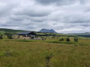 a house in a field with mountains in the background at Adorable cosy and private new cabin in the south in Hvolsvöllur