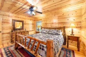 Dormitorio en cabaña de madera con cama y ventilador de techo en Large Cabin with views of Beautiful NC Mountains, en Murphy