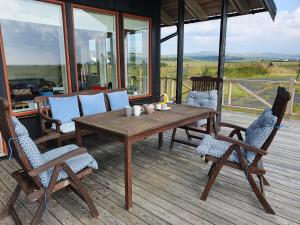 una mesa de madera y sillas en una terraza de madera en Adorable cosy and private new cabin in the south en Hvolsvöllur