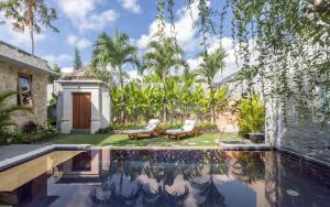 a swimming pool with two chairs and a house at Bali Voyage in Seminyak