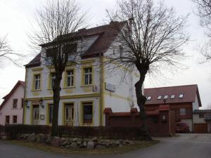 une maison jaune et blanche avec deux arbres devant elle dans l'établissement Gasthof Bergquelle, à Wandlitz