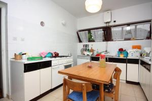 a kitchen with a wooden table and white cabinets at Double Room Banjol 5077b in Rab +16 photos