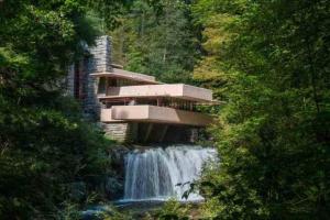 a building on top of a waterfall next to a river at Stay In Ohiopyle near the GAP Trail - Ohiopyle, PA in Farmington