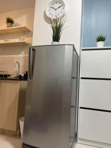 a refrigerator in a kitchen with a clock on the wall at 1 BR Cozy Modern-Style Condo with Balcony & 5-star amenities at Wind Residences in Tagaytay
