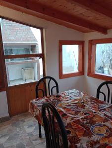 comedor con mesa, sillas y ventanas en Mi Refugio en Río Gallegos