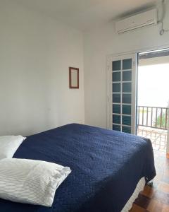 a bedroom with a blue bed and a sliding glass door at Pé na areia 6 quartos Ingleses in Florianópolis