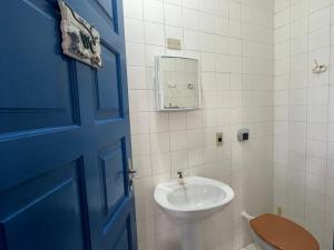 a bathroom with a sink and a toilet and a blue door at Pé na areia 6 quartos Ingleses in Florianópolis