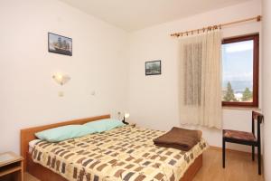 a bedroom with a bed and a window at Apartments and rooms with parking space Vrbnik, Krk - 5301 in Vrbnik