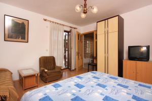 a bedroom with a bed and a chair and a tv at Apartment Vrbnik 5301b in Vrbnik