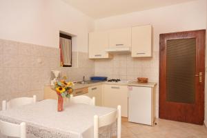 a kitchen with a table with a vase of flowers on it at Apartment Vrbnik 5301b in Vrbnik