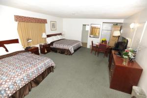 Habitación de hotel con 2 camas y escritorio en Victoria Motel, en Ventura