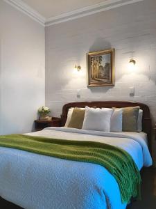 Victoria House Motor Inn في كرويدون: غرفة نوم بسرير كبير مع بطانية خضراء