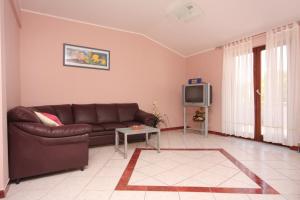 a living room with a brown couch and a tv at Apartments and rooms with parking space Vrbnik, Krk - 5302 in Vrbnik