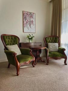 Duas cadeiras e uma mesa numa sala de estar em Victoria House Motor Inn em Croydon