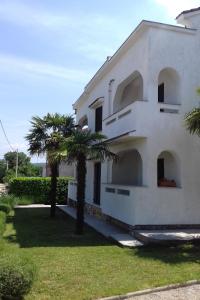 a white house with two palm trees in front of it at Apartments with a parking space Sveti Anton, Krk - 5288 in Sveti Anton