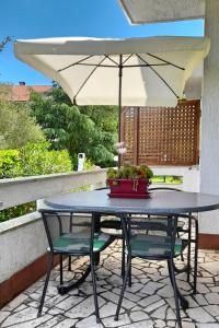 a table with two chairs and an umbrella on a patio at Apartments with a parking space Sveti Anton, Krk - 5288 in Sveti Anton