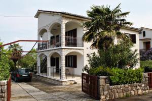 a white house with a palm tree in front of it at Apartments with a parking space Malinska (Krk) - 5284 in Malinska