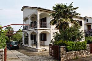 una casa blanca con una palmera delante de ella en Apartment Malinska 5284a en Malinska