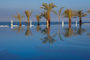 a group of palm trees and the water with sailboats at King Evelthon Beach Hotel & Resort in Paphos