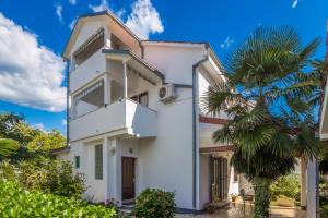 a white house with a palm tree in front of it at Apartments with a parking space Vantacici, Krk - 5313 in Malinska