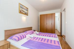 two beds in a room with purple and pink pillows at Apartment Vantacici 5313c in Malinska