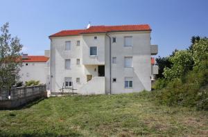 a building on a hill next to a yard at Apartments and rooms with parking space Sveti Vid, Krk - 5323 in Sveti Vid-Miholjice