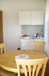 a kitchen with a wooden table with chairs and a kitchenventory at Apartments and rooms with parking space Sveti Vid, Krk - 5323 in Sveti Vid-Miholjice
